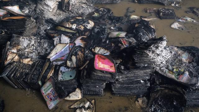 Verbrannte Bücher, die kaum mehr zu erkennen sind, aus einem Warenlager