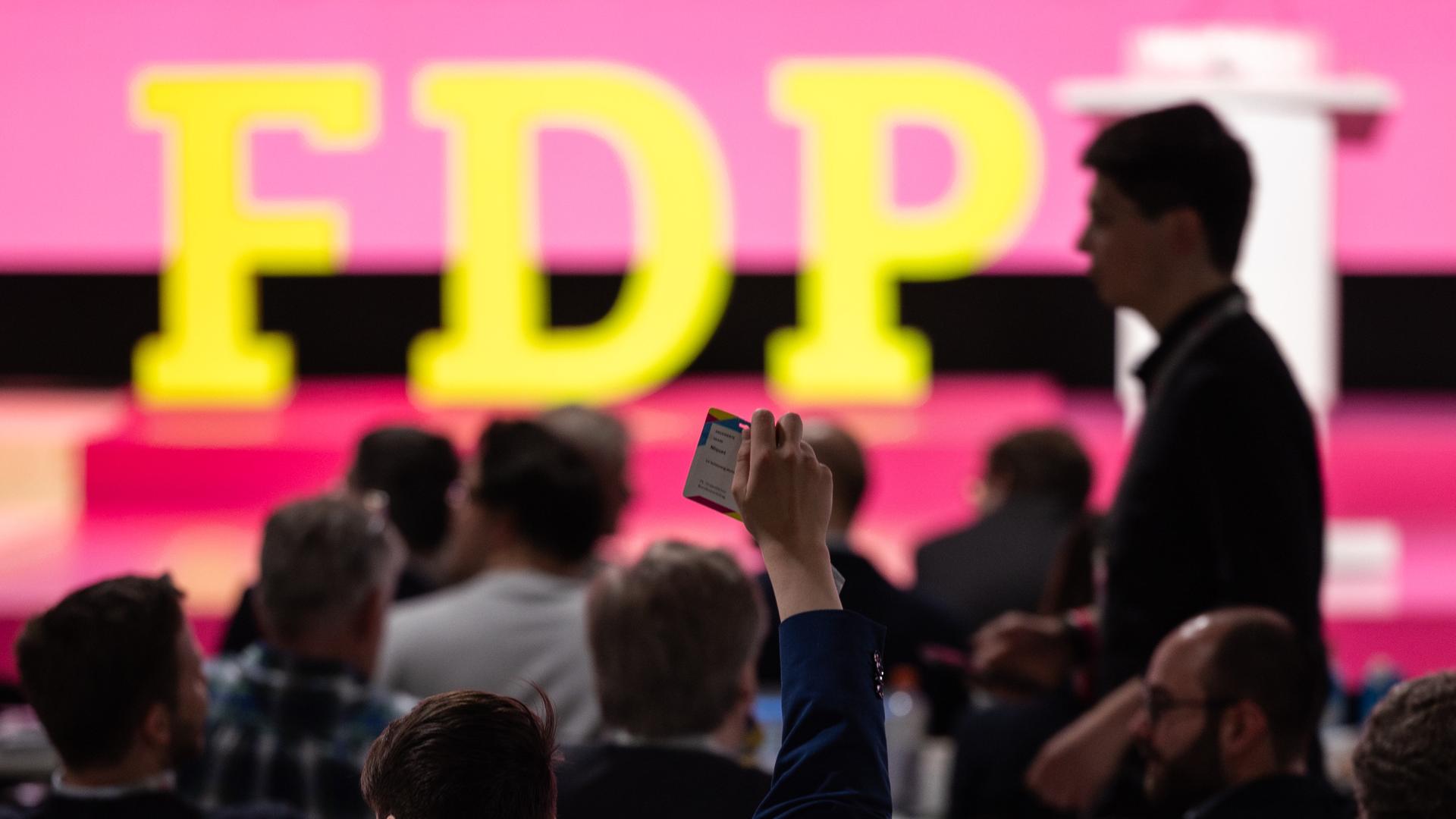 Publikum sitzt vor einer Bühne, auf der das Logo der FDP steht. 