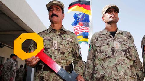 Ein Mitglied der afghanischen Zivilpolizei (ANCOP) hält einen symbolischen Schlüssel während der Übergabezeremonie eines deutschen Stützpunktes an die afghanischen Streitkräfte in Kundus am 6. Oktober 2013. 
