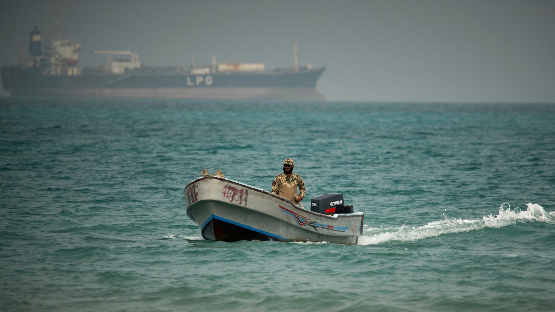 Vor dem Hintergrund eines LPG-Tankers fährt ein Motorboot mit einem jemenitischen Soldaten in den Gewässern der Meerenge Bab el-Mandab. Vor dem Hintergrund eines LPG-Tankers fährt ein Motorboot mit einem jemenitischen Soldaten in den Gewässern der Meerenge Bab el-Mandab.