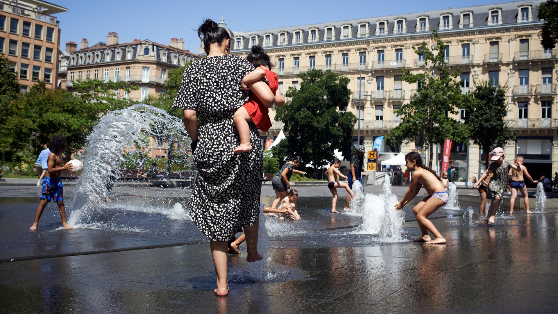 Kinder kühlen sich an einem Stadtbrunnen während der Hitzewelle 2022 in Toulouse.