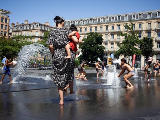Kinder kühlen sich an einem Stadtbrunnen während der Hitzewelle 2022 in Toulouse.