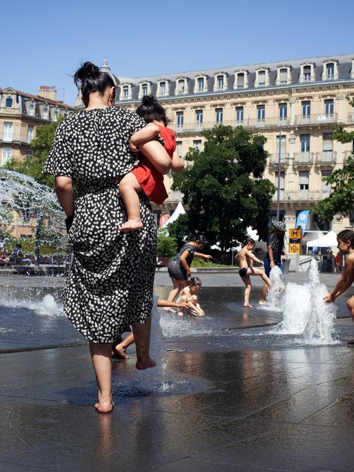 Kinder kühlen sich an einem Stadtbrunnen während der Hitzewelle 2022 in Toulouse.