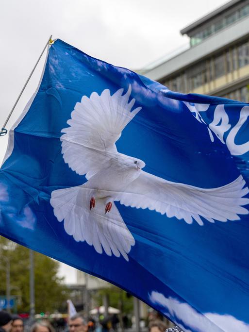 Fahne mit Friedenstaube bei der Demonstration "Die Waffen nieder" am Breitscheidplatz in Berlin. Die Veranstaltung richtet sich gegen jegliche Kriege und fordert den sofortigen Stopp aller Waffenlieferungen. Berlin, 03.10.2024