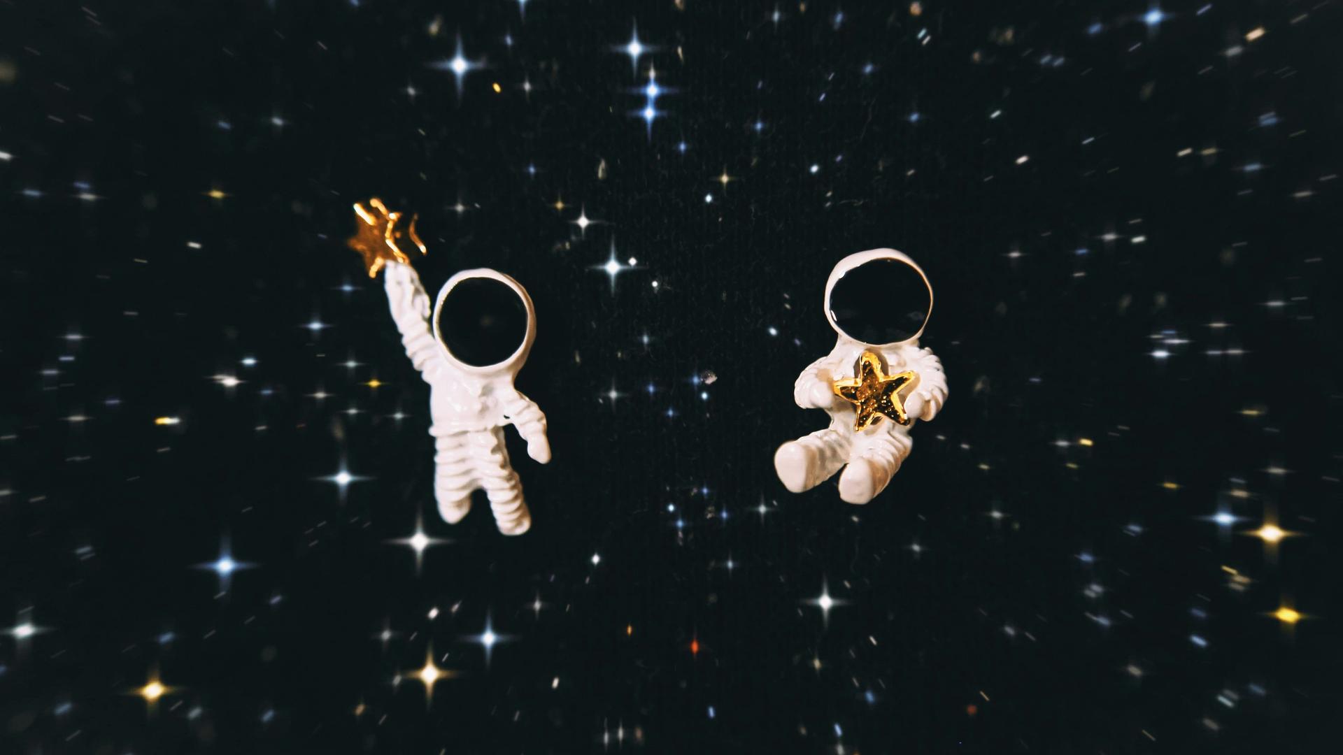 Zwei Astronauten mit je einem Stern in der Hand im Weltall.