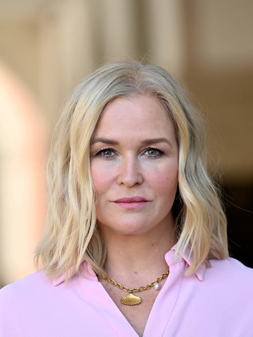 Judith Hoersch trägt ein rosafarbenes Oberteil und eine goldene Kette. Sie schaut direkt in die Kamera.