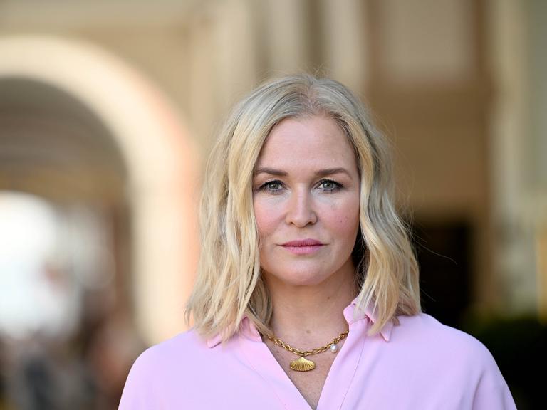 Judith Hoersch trägt ein rosafarbenes Oberteil und eine goldene Kette. Sie schaut direkt in die Kamera.