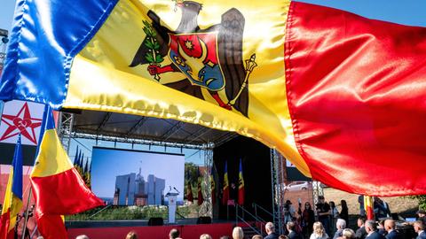 Das Bild zeigt die Nationalflagge Moldaus vor dem Hintergrund einer Wahlkampfveranstaltung.