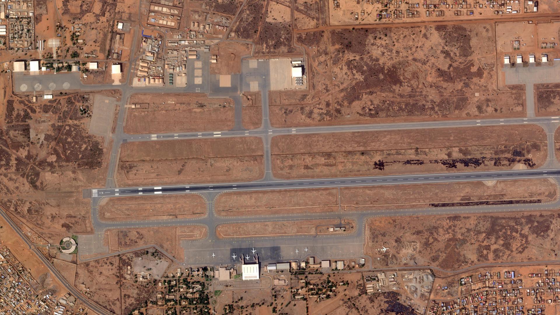 Die Aufnahme aus der Luft zeigt Start- und Landebahnen in einer rötlichen Landschaft. Danben stehe mehrere Flughafengebäude. Die Aufnahme aus der Luft zeigt Start- und Landebahnen in einer rötlichen Landschaft. Danben stehe mehrere Flughafengebäude.