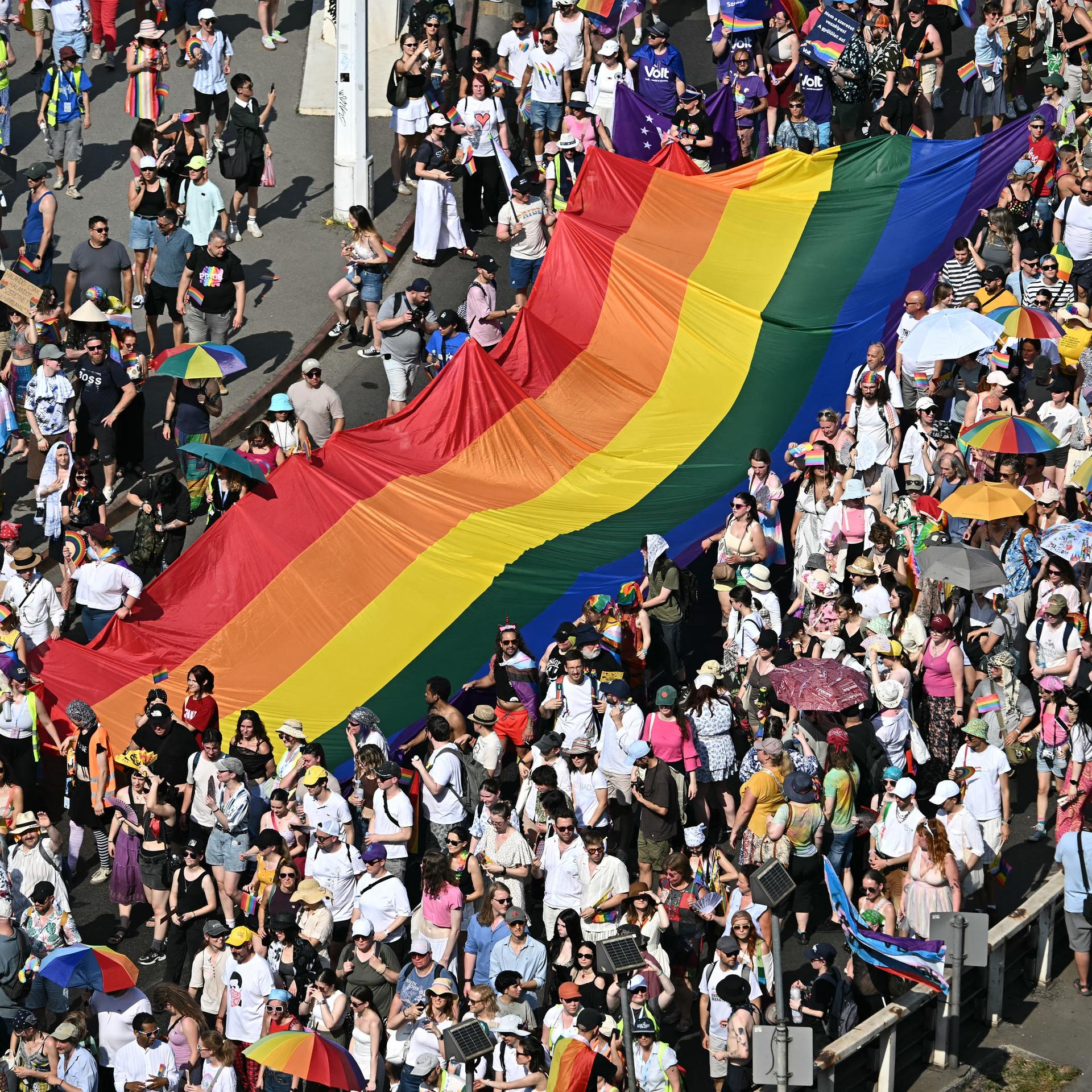 Teilnehmer der Pride Parade in Budapest tragen eine große Regenfahne durch die Menge. 