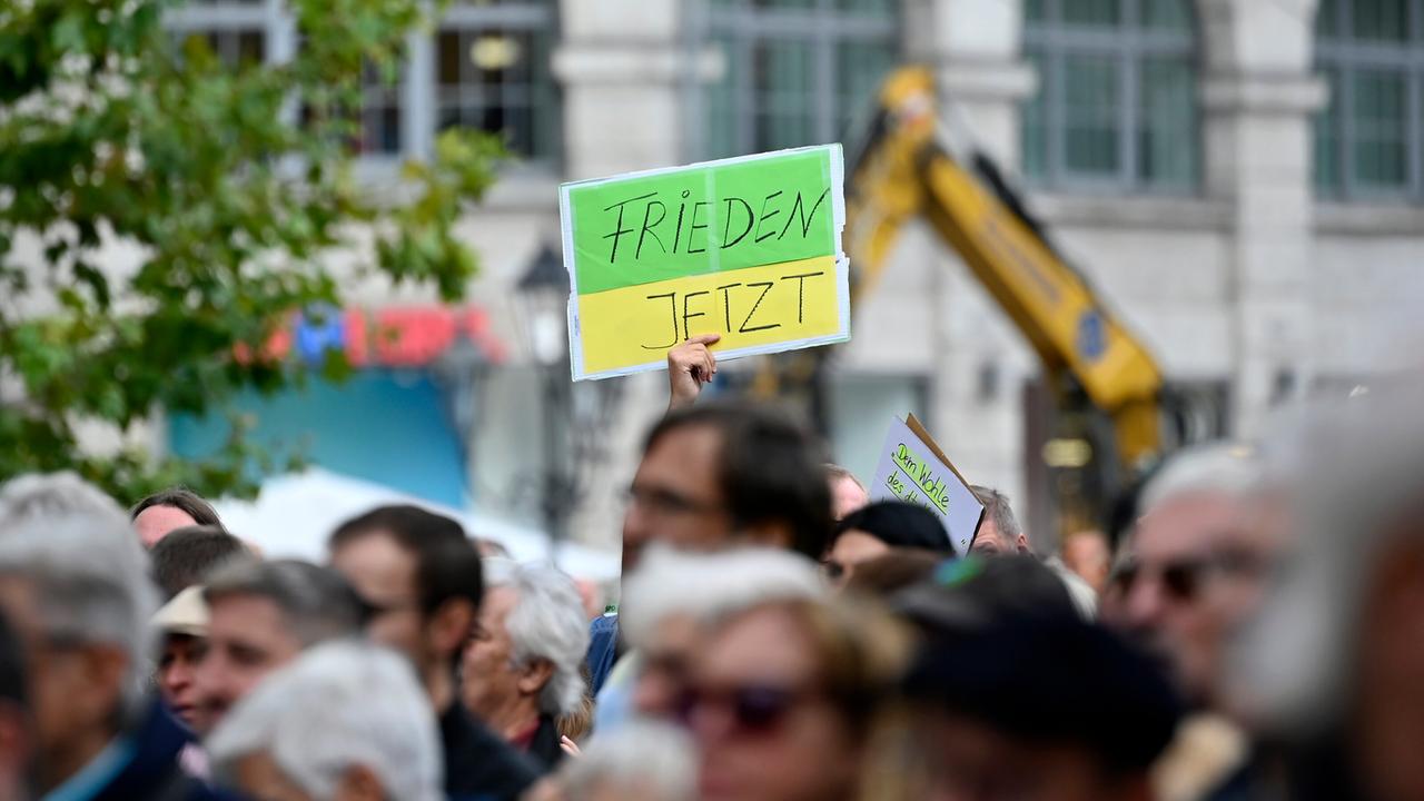 Ein Gegendemonstrant hält ein Schild hoch mit der Aufschrift 'Frieden jetzt' bei einer Kundgebung der Bayerischen SPD.  