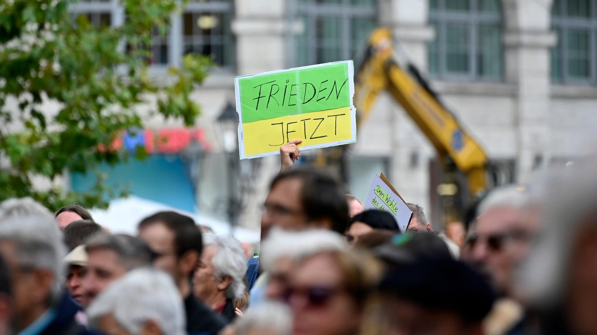 Ein Gegendemonstrant hält ein Schild hoch mit der Aufschrift 'Frieden jetzt' bei einer Kundgebung der Bayerischen SPD.  