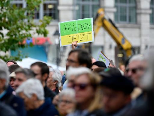 Ein Gegendemonstrant hält ein Schild hoch mit der Aufschrift 'Frieden jetzt' bei einer Kundgebung der Bayerischen SPD.  