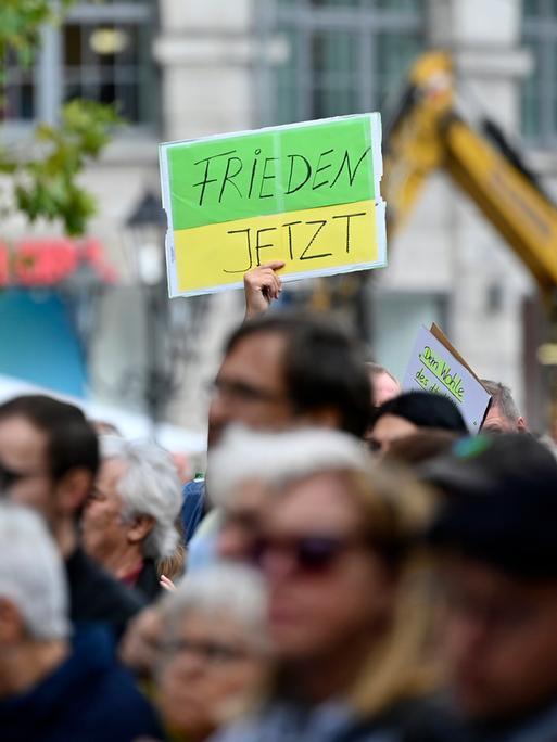 Ein Gegendemonstrant hält ein Schild hoch mit der Aufschrift 'Frieden jetzt' bei einer Kundgebung der Bayerischen SPD.  