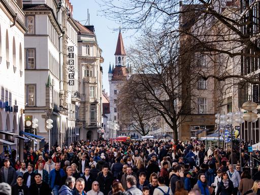 Zahlreiche Menschen gehen in der Innenstadt von München an Geschäften an der Kaufingerstraße vorüber.