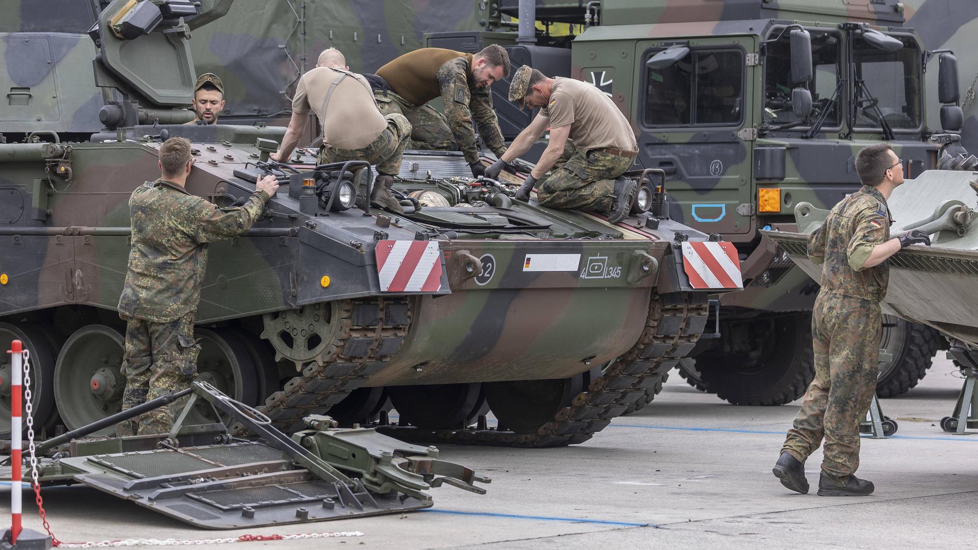 Eine Panzerhaubitze 2000 der Bundeswehr wird instand gesetzt, mehrere Soldaten arbeiten mit Werkzeug auf dem Panzer.