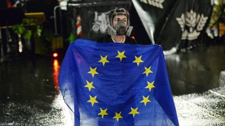 Eine Demonstrantin mit Schutzmaske hält in der georgischen Hauptstadt Tiflis eine EU-Flagge.