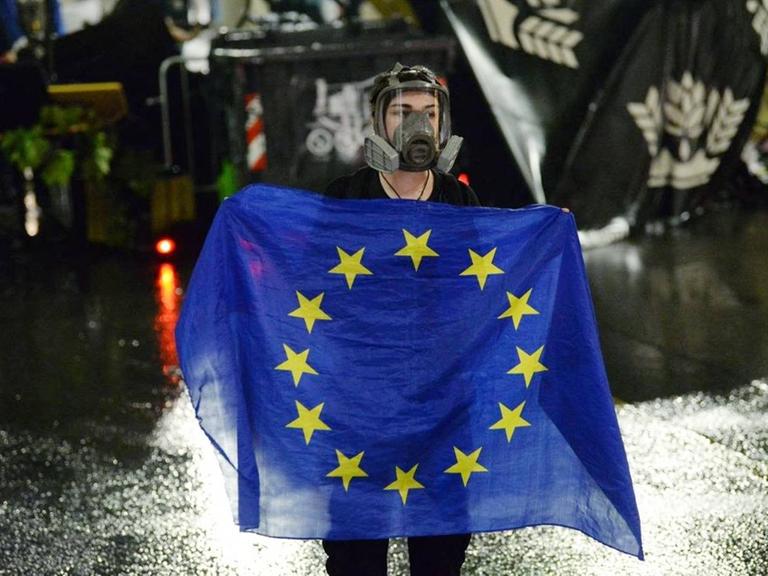 Eine Demonstrantin mit Schutzmaske hält in der georgischen Hauptstadt Tiflis eine EU-Flagge.