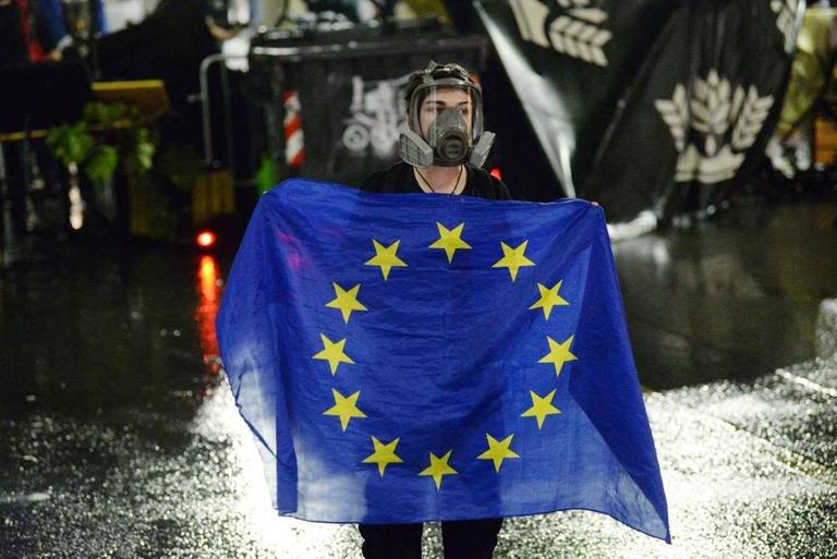 Eine Demonstrantin mit Schutzmaske hält in der georgischen Hauptstadt Tiflis eine EU-Flagge.