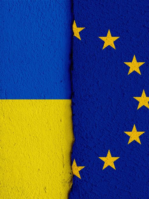 [M] Die Nationalflagge der Ukraine und die Flagge der Europäischen Union auf einer Wand mit einem vertikalen Absatz bzw. Riss in der Mitte und zwei unterschiedlichen Putzarten. Foto mit Composing als Symbolbild für das Verhältnis zwischen der Ukraine und der EU.