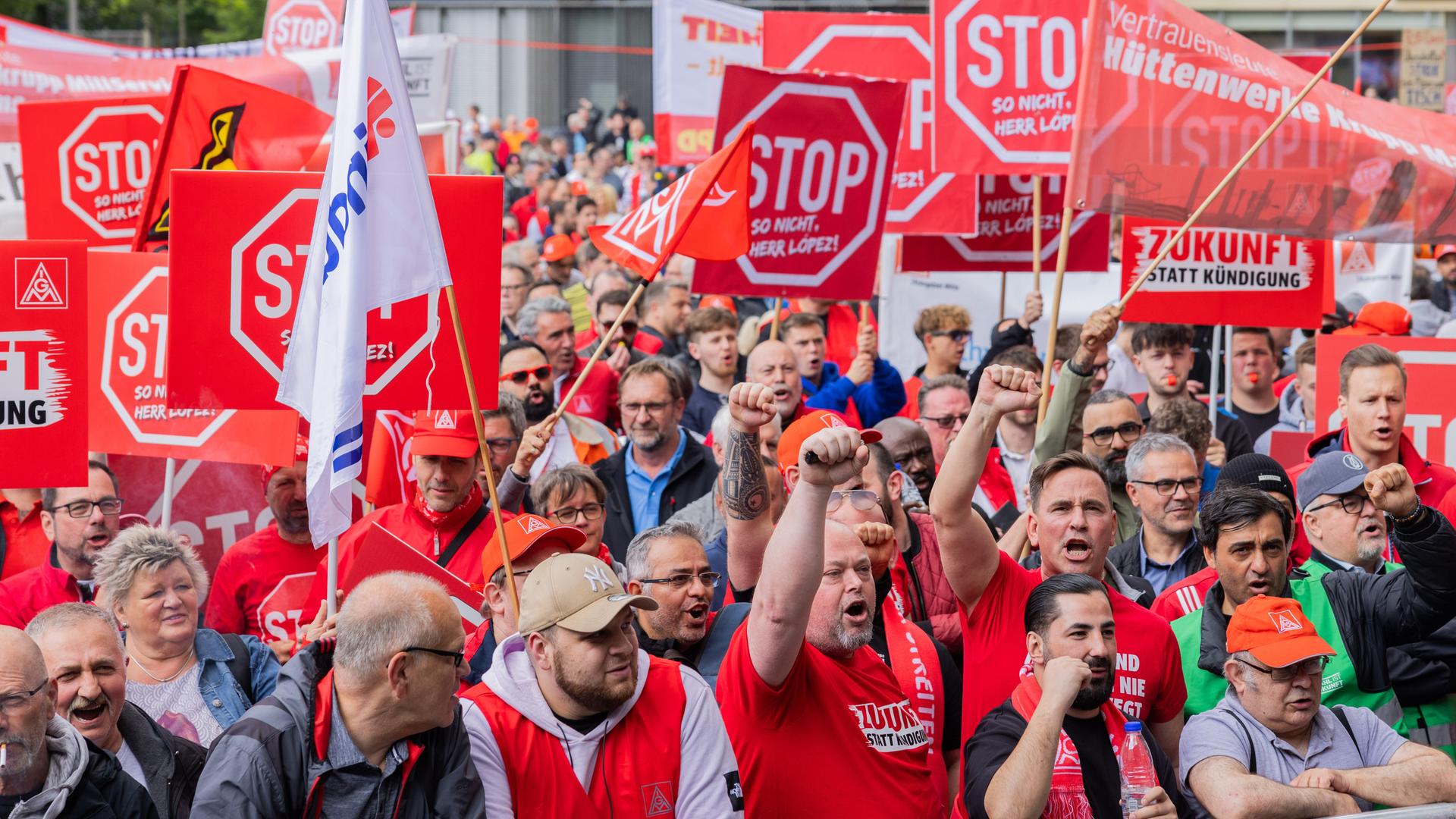 Mitarbeitende halten rote Plakate mit der Aufschrift "Stop" in die Luft.