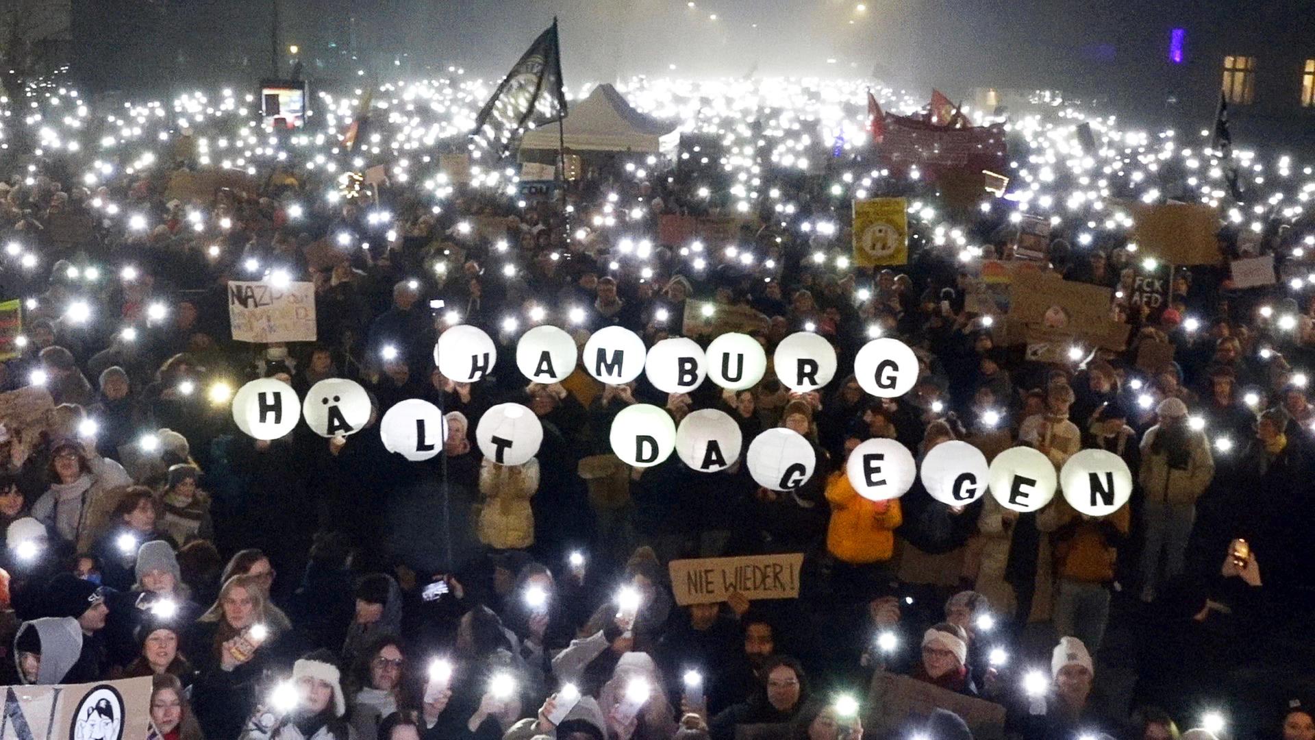 Zehntausende Menschen nehmen an einer Demonstration gegen die Migrationspolitik der CDU in der Innenstadt teil und halten Laternen hoch mit dem Schriftzug "Hamburg hält dagegen". 