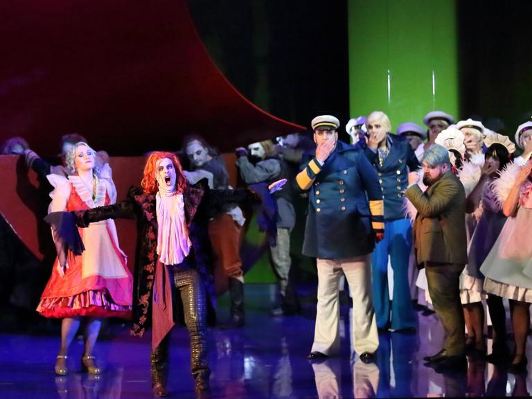 Die Solisten und der Chor der "Holländer"-Inszenierung stehen in bunten Kostümen auf der Bühne der Komischen Oper
