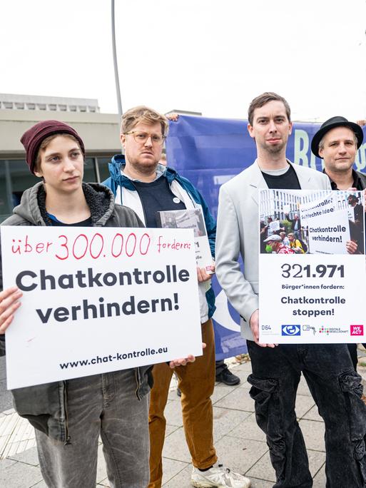 Mitglieder des Bündnis «Chatkontrolle Stoppen!» demonstrieren vor dem Bundesinnenministerium und präsentieren gesammelte Unterschriften. Sie halten Schilder vor sich.