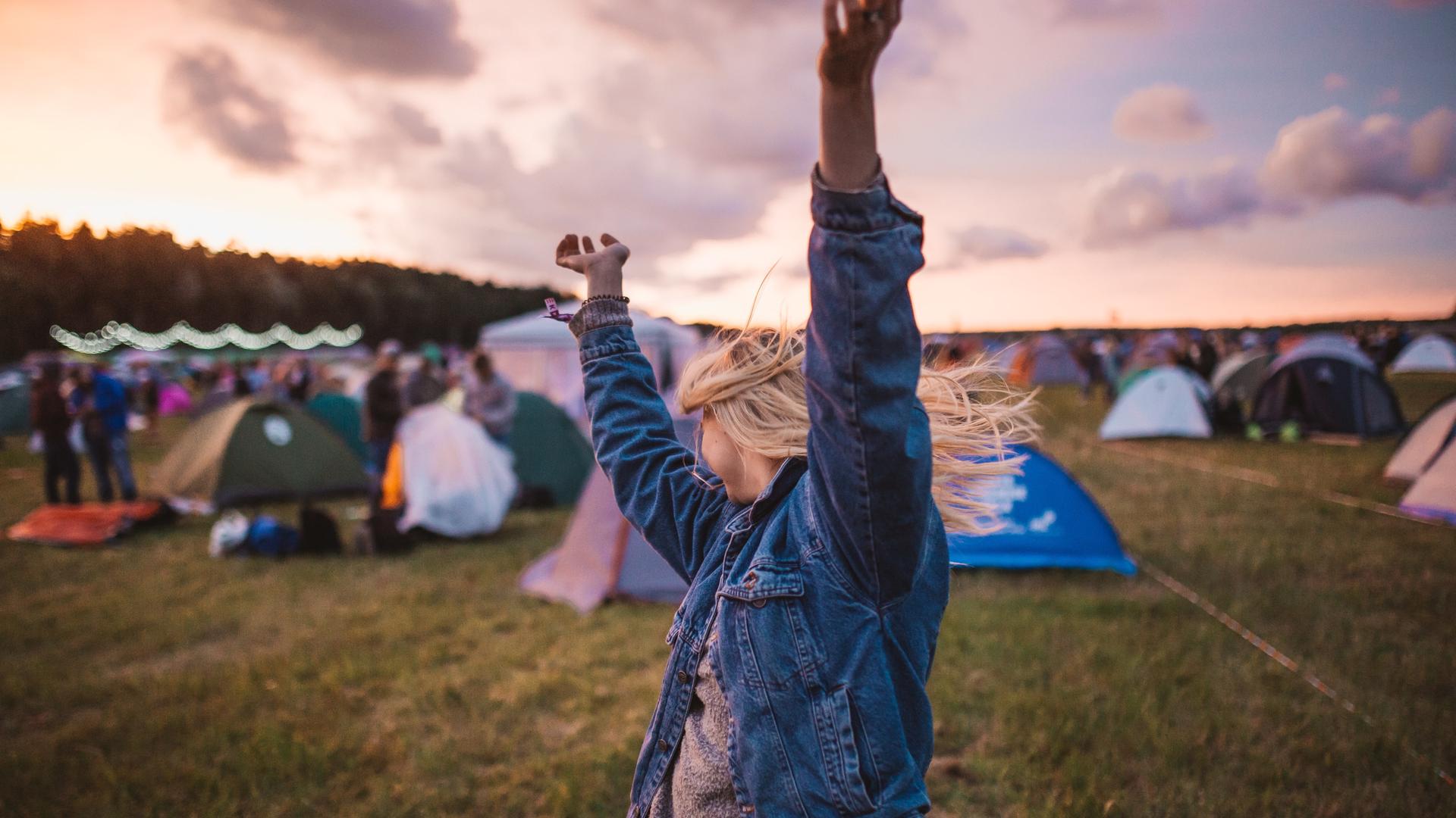 Einen glückliche Frau tanzend auf dem Positivus Festival in Lettland. Im Hintergrund sind Zelte zu sehen. Einen glückliche Frau tanzend auf dem Positivus Festival in Lettland. Im Hintergrund sind Zelte zu sehen.