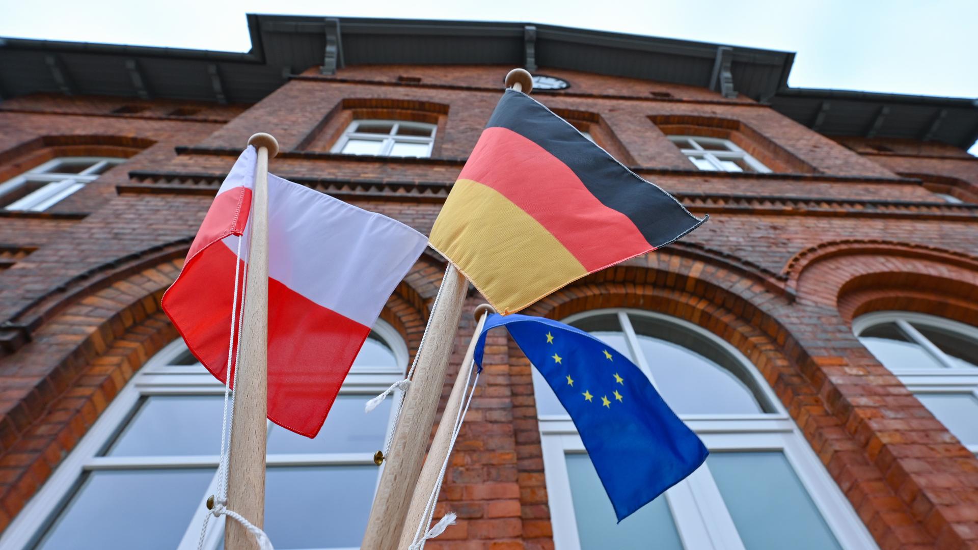 Kleine Fähnchen der Länder Polen und Deutschland sowie der EU wehen im Wind vor dem Gebäude des Seelower Bahnhofes