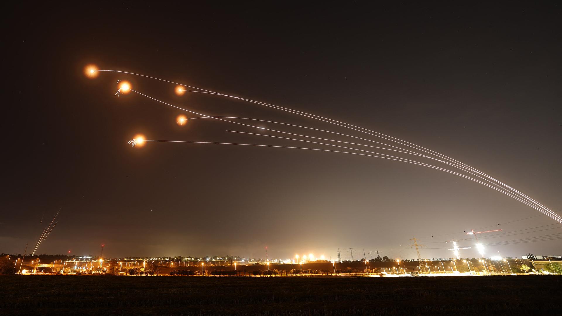 Das israelische Flugabwehrsystem "Iron Dome" schießt Raketen ab. Im nächtlichen Himmel sind helle Blitze von Explosionen zu sehen