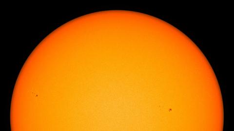 Aufnahme der Sonne als orangenem Punkt vor schwarzem Hintergrund.