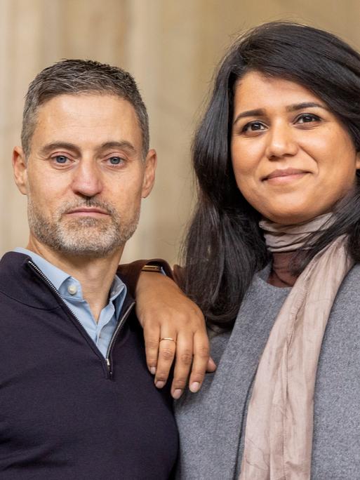 Saba-Nur Cheema lehnt ihren Unterarm auf die Schulter von Meron Mendel. Er schaut ernst in die Kamera, sie lächelt. Saba-Nur Cheema lehnt ihren Unterarm auf die Schulter von Meron Mendel. Er schaut ernst in die Kamera, sie lächelt.