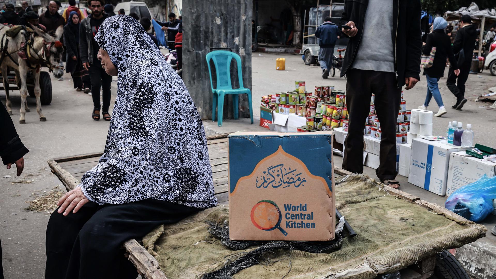 Eine Frau in Rafah im Gazastreifen sitzt neben einer Kiste mit Lebensmitteln der Hilfsorganisation World Central Kitchen Eine Frau in Rafah im Gazastreifen sitzt neben einer Kiste mit Lebensmitteln der Hilfsorganisation World Central Kitchen