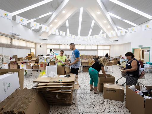 Im Freiwilligen-Hilfe-Zentrum für Reservisten in Aschdod stehen mehrer Menschen zwischen vielen Kartons.