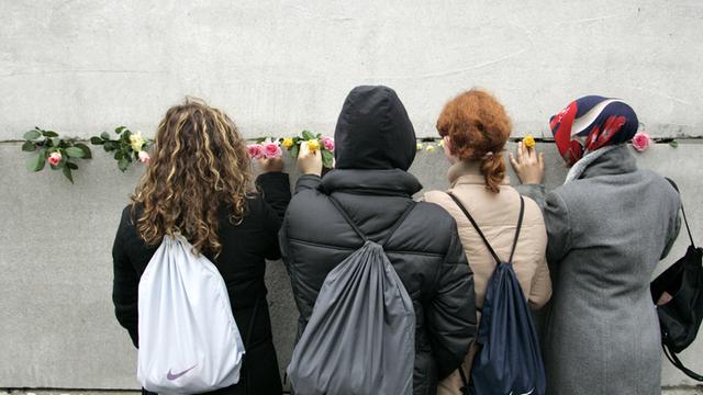 Junge Frauen stecken Blumen in eine Mauerritze