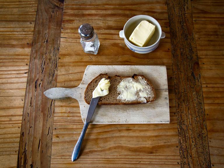 Salz, Butter und Brot auf einem Brettchen. 