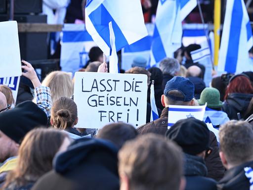 Auf einer Israel-Solidaritätsdemonstration mit vielen Flaggen, wird ein Plakat hochgehalten mit der Aufschrift "LASST DIE GEISELN FREI!"