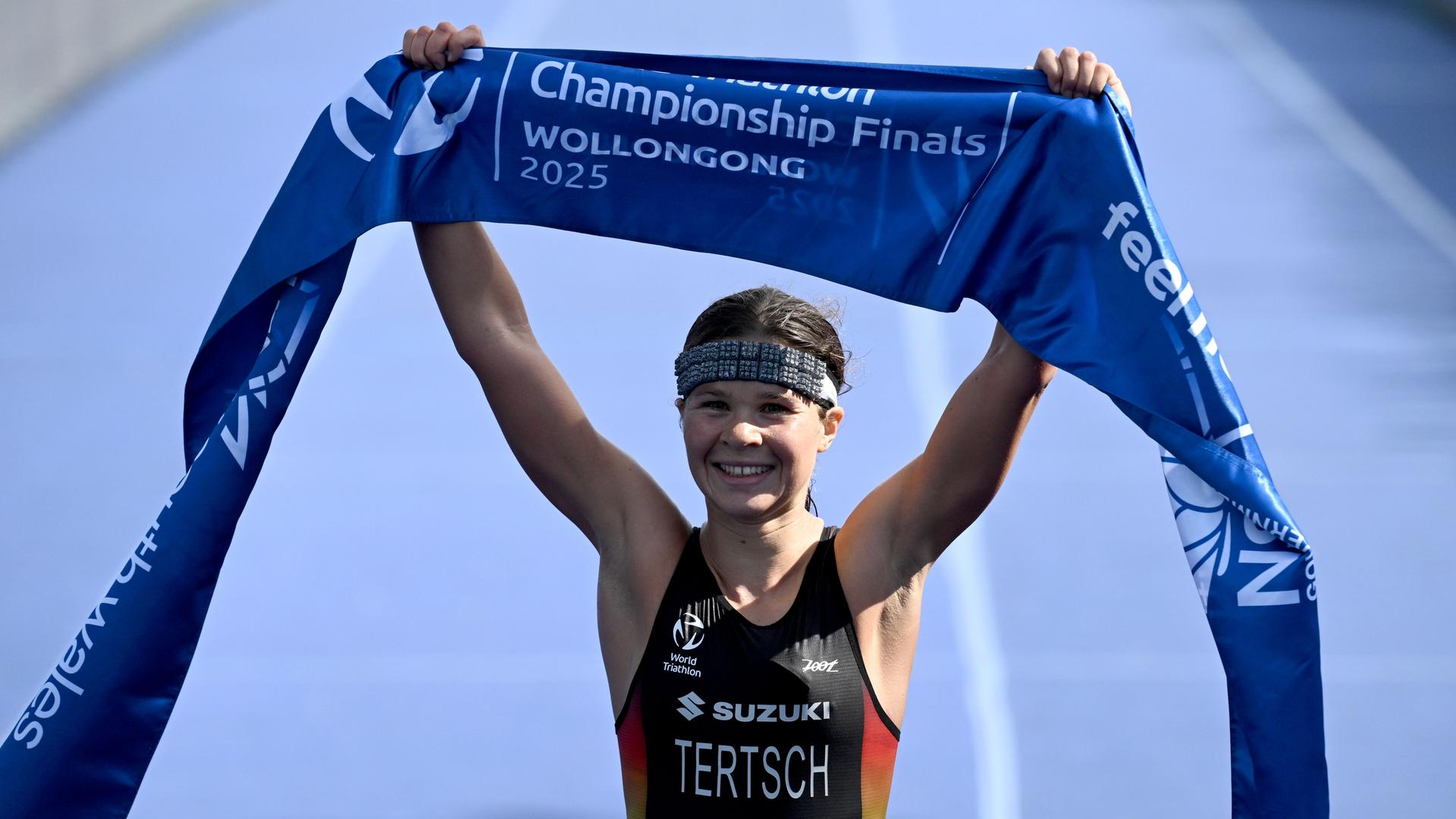 Lisa Tertsch aus Deutschland hält ein Band mit der Aufschrift "Championship Finals Wollongong 2025" in die Höhe.