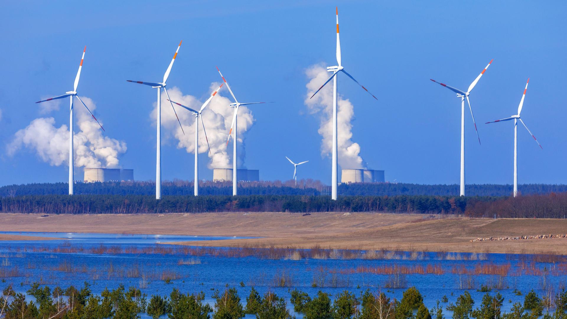 Blick auf den Cottbuser Ostsee, einen gefluteten Tagebau, mit Kraftwerk Jänschwalde und Windrädern am Horizont