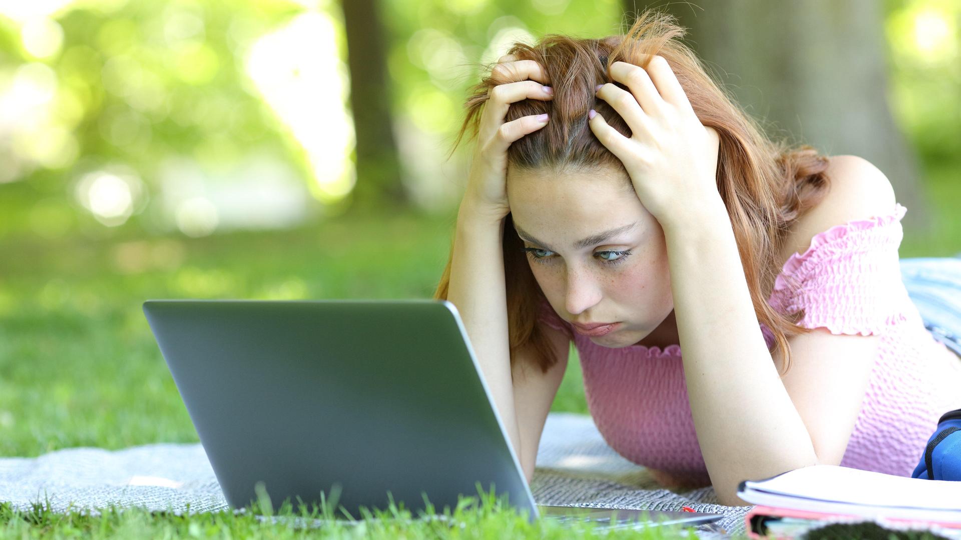 Ein Mädchen schaut auf ihr Laptop und rauft sich in den Haaren.