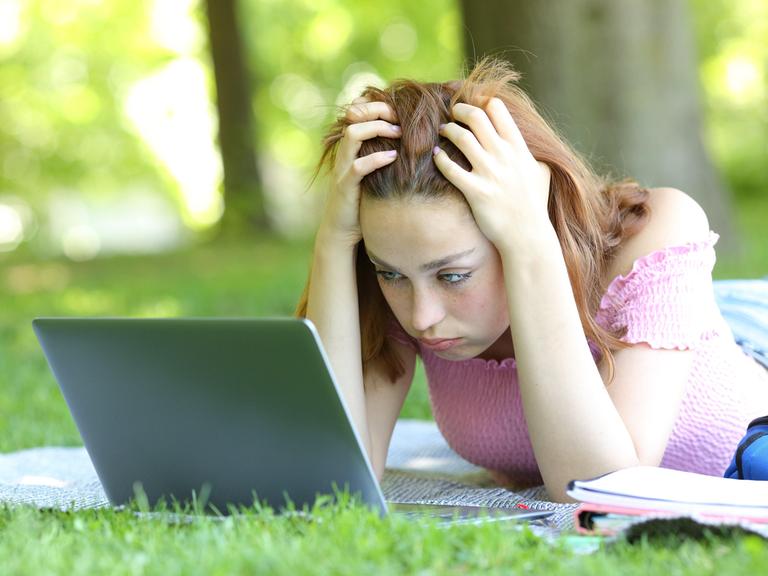 Ein Mädchen schaut auf ihr Laptop und rauft sich in den Haaren. Ein Mädchen schaut auf ihr Laptop und rauft sich in den Haaren.