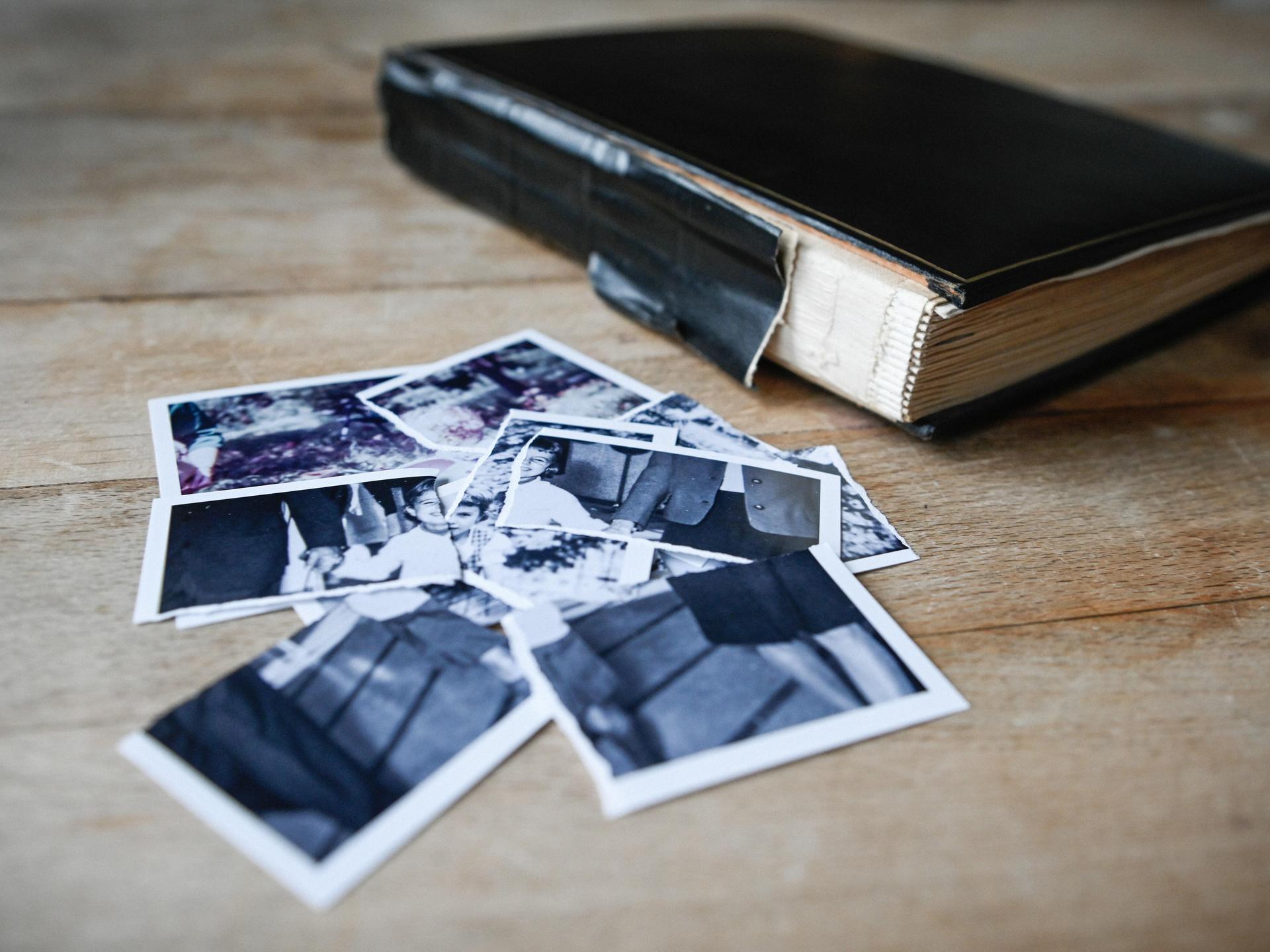Zerrissene Kinderbilder liegen auf einem kleinen Haufen neben einem Fotoalbum auf einem Tisch am 27. Januar 2022 in Bonn.