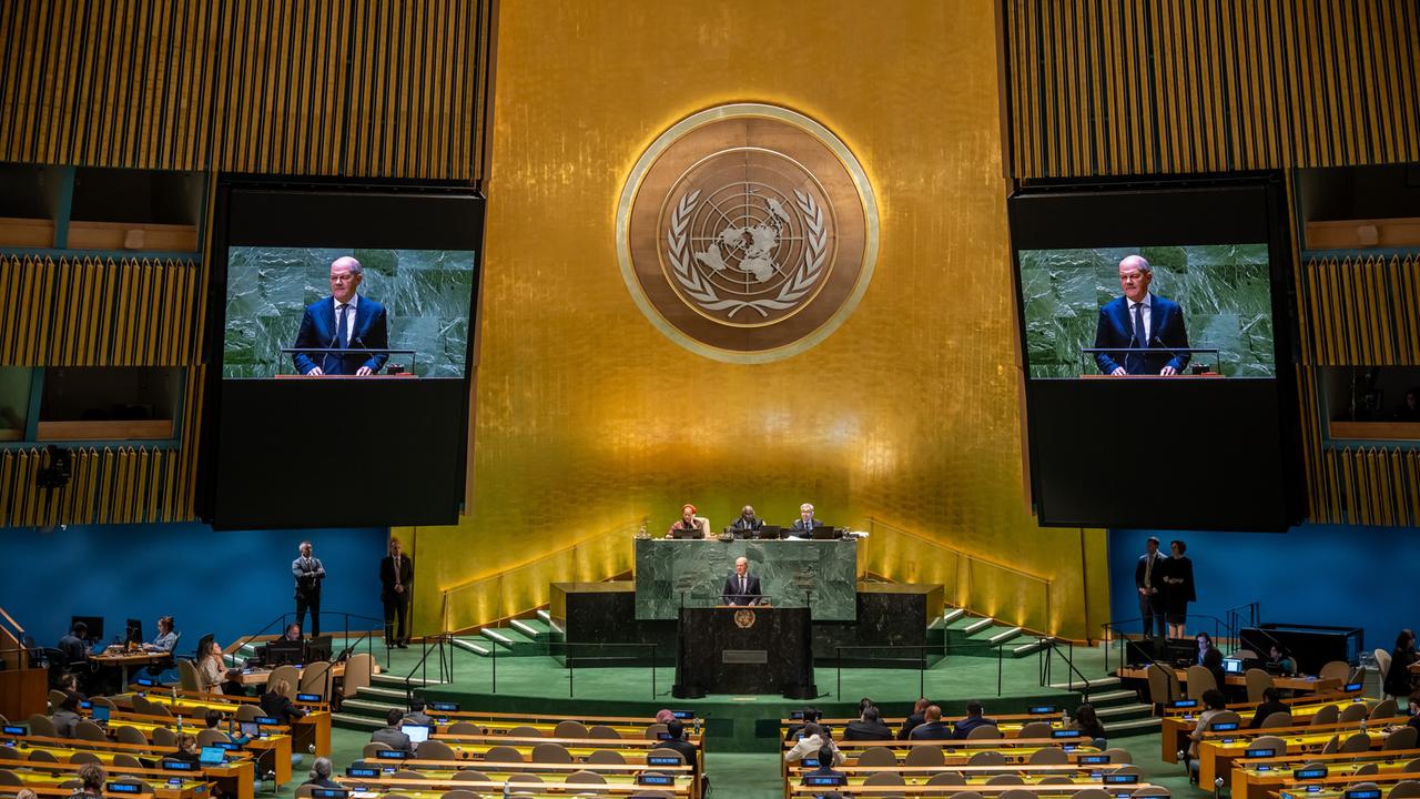 Bundeskanzler Olaf Scholz am Rednerpult der UN-Vollversammlung unter dem riesigen Symbol der Vereinten Nationen. 