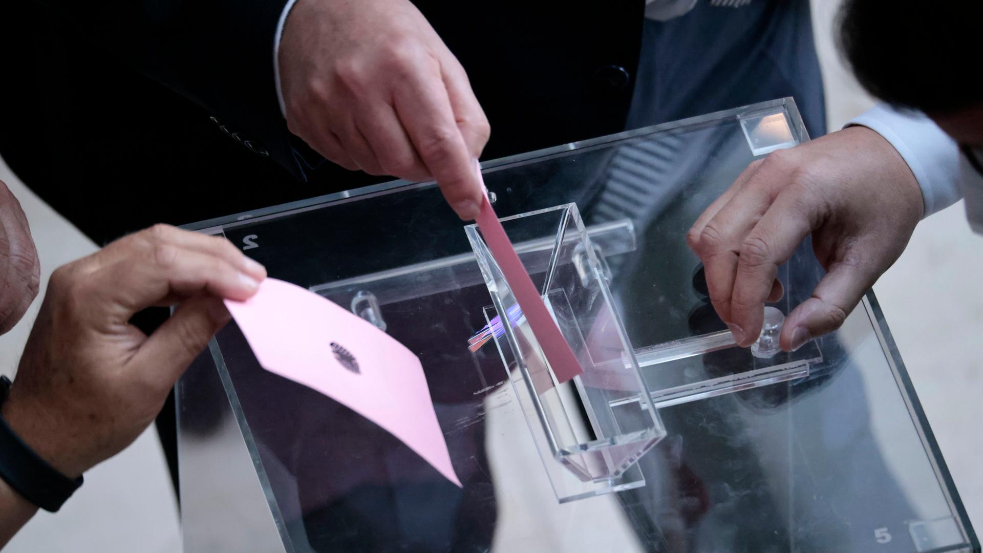 Abgeordnete des Bundestags werfen rosa Stimmzettel in eine Wahlurne, um über die Impfpflicht abzustimmen. 