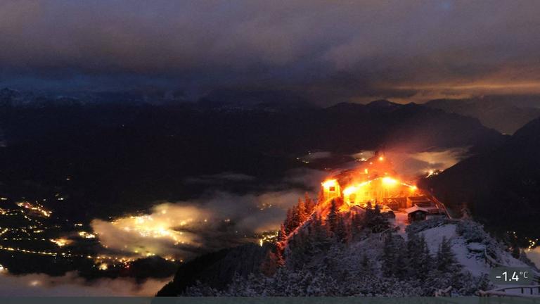 Der Screenshot einer Webcam zeigt ein brennedes Gebäude auf einem Bergbei Nacht.