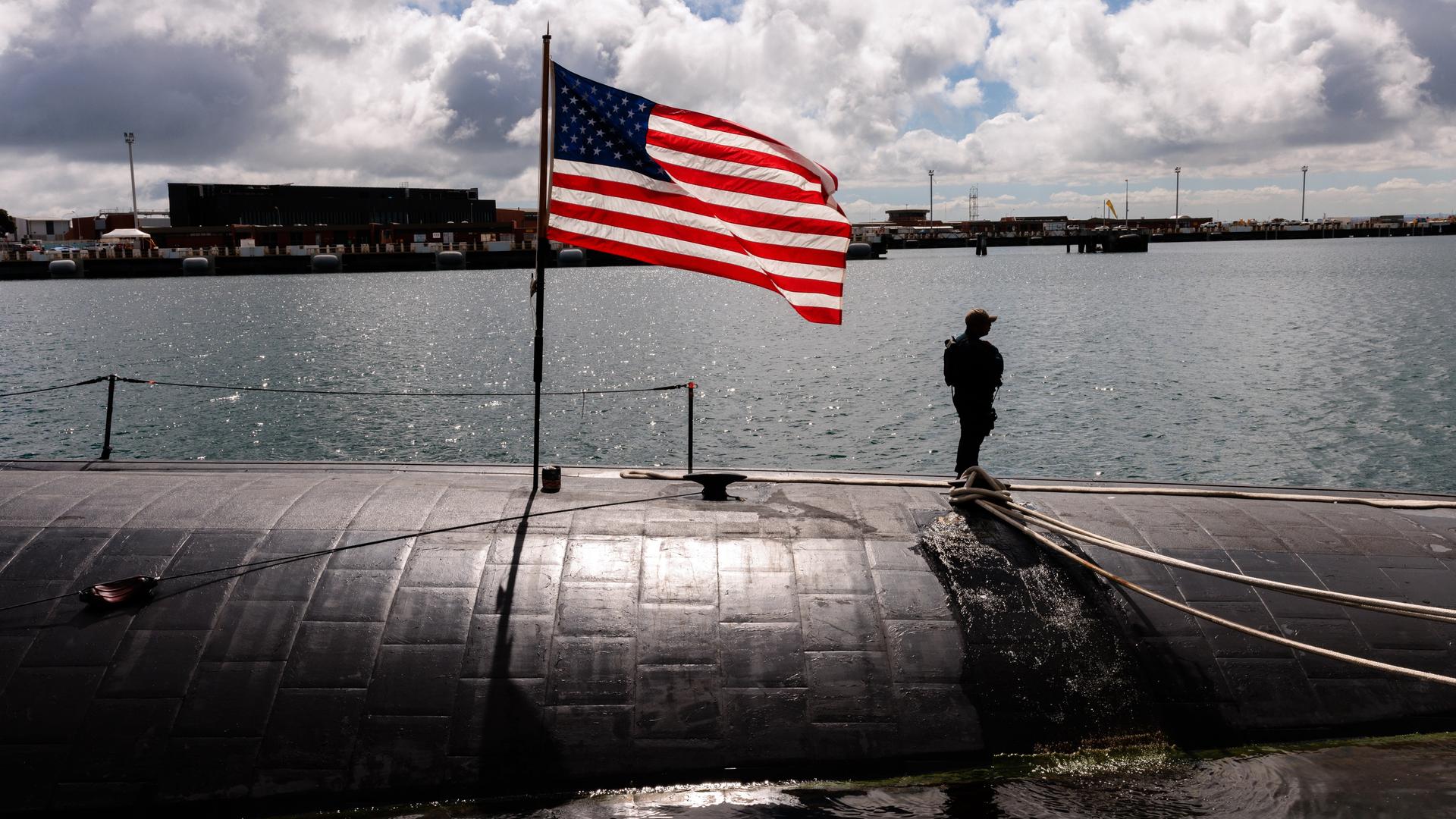 Ein Besatzungsmitglied steht neben einer US-Flagge auf der USS Asheville, einem atomgetriebenen U-Boot, auf dem Stützpunkt der Royal Australian Navy in Perth.