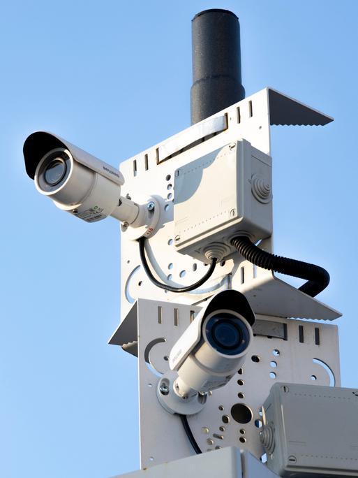 Mehrere Überwachungskameras an einem Pfahl weisen in unterschiedliche Richtungen.