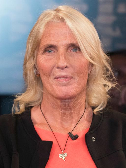 Heike Rath sitzt im Fernsehstudio. Sie hat schulterlanges blondes Haar und trägt eine Halskette mit einem silbernen Elefantenkopf.