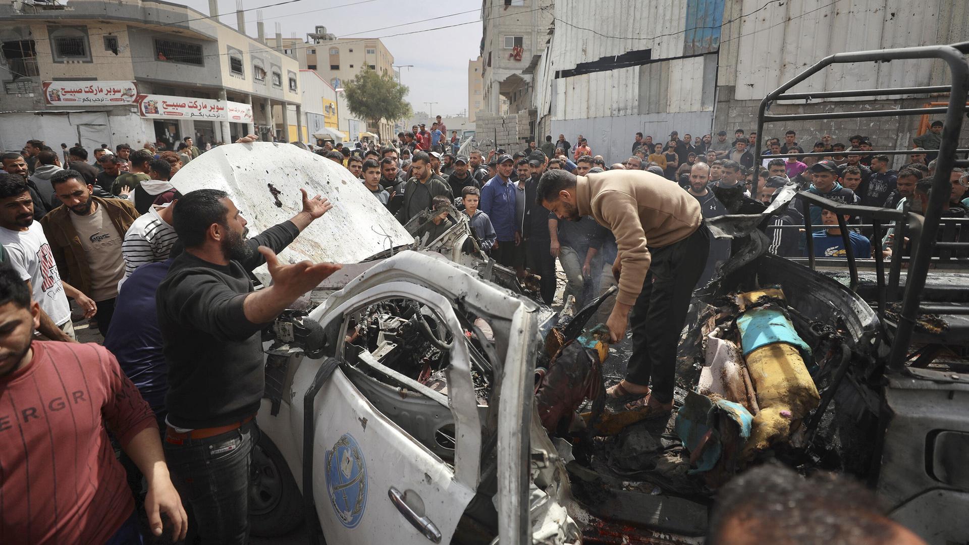Palästinenser untersuchen ein beschädigtes Auto, nach einem israelischen Luftangriff auf ein Polizeifahrzeug.